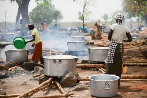 Naiset laittavat ruokaa avotulella Adjumanin pakolaisasutusaleelta Ugandasta