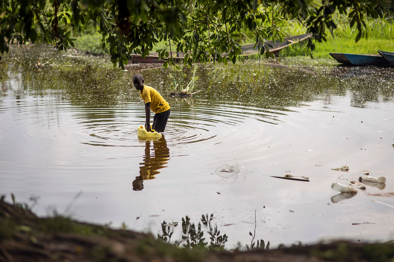 Poika kerää vettä saastuneesta järvestä pakolaisasutusalueella Ugandassa