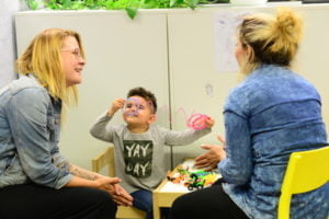 Pakolaisavun ohjaaja Jenny Joensuu keskustelee maahanmuuttajataustaisen äidin kanssa hänen lapsensa leikkiessä vieressä