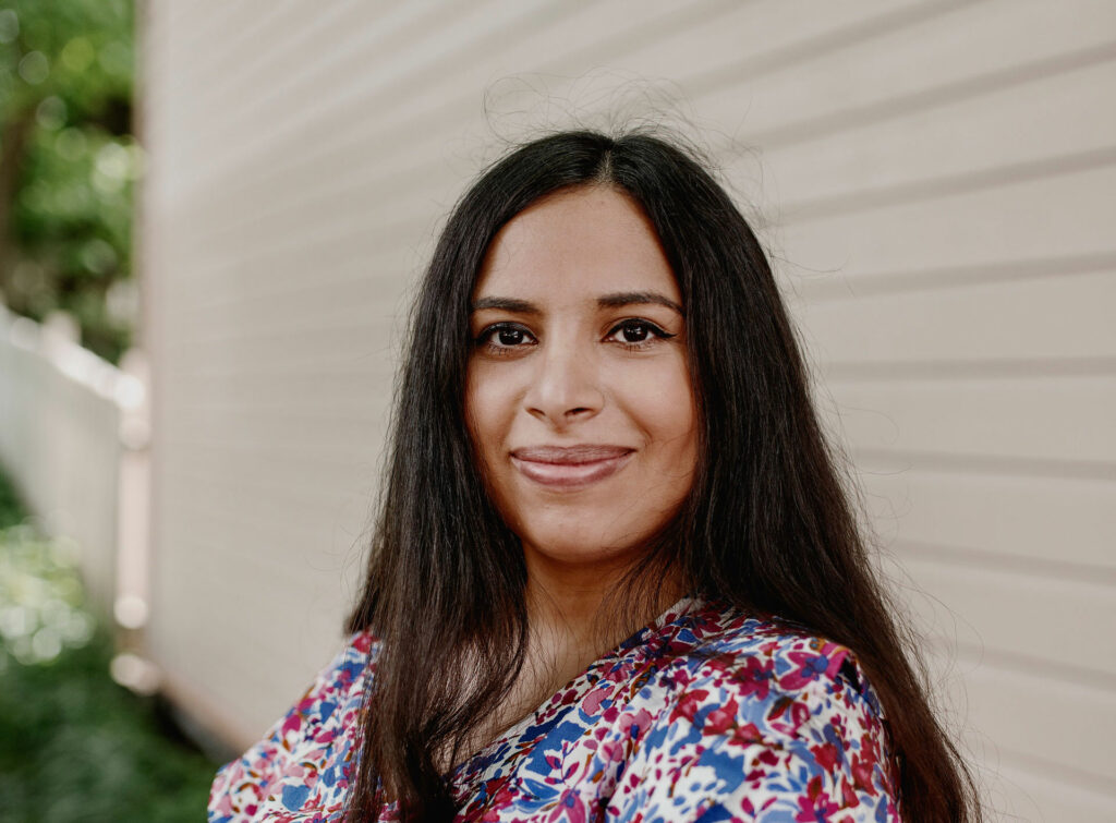 Vuoden pakolaisnainen 2021 Sara Al Husaini hymyilee kameralle kukkamekossa.