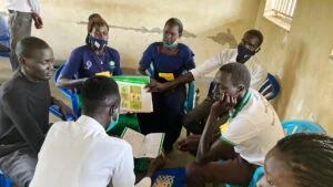 Kuusi Ugandan koulutukseen osallistuvia aikuista istuu pöydän äärellä.