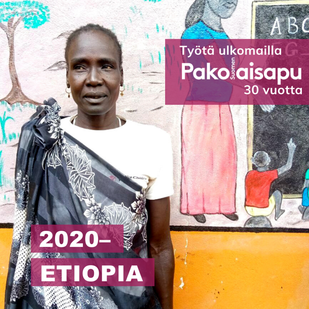 Henkilö seisoo maalatun seinän edustalla. Teksti: "Pakolaisapu, työtä ulkomailla 30 vuotta. 2020 - Etiopia".