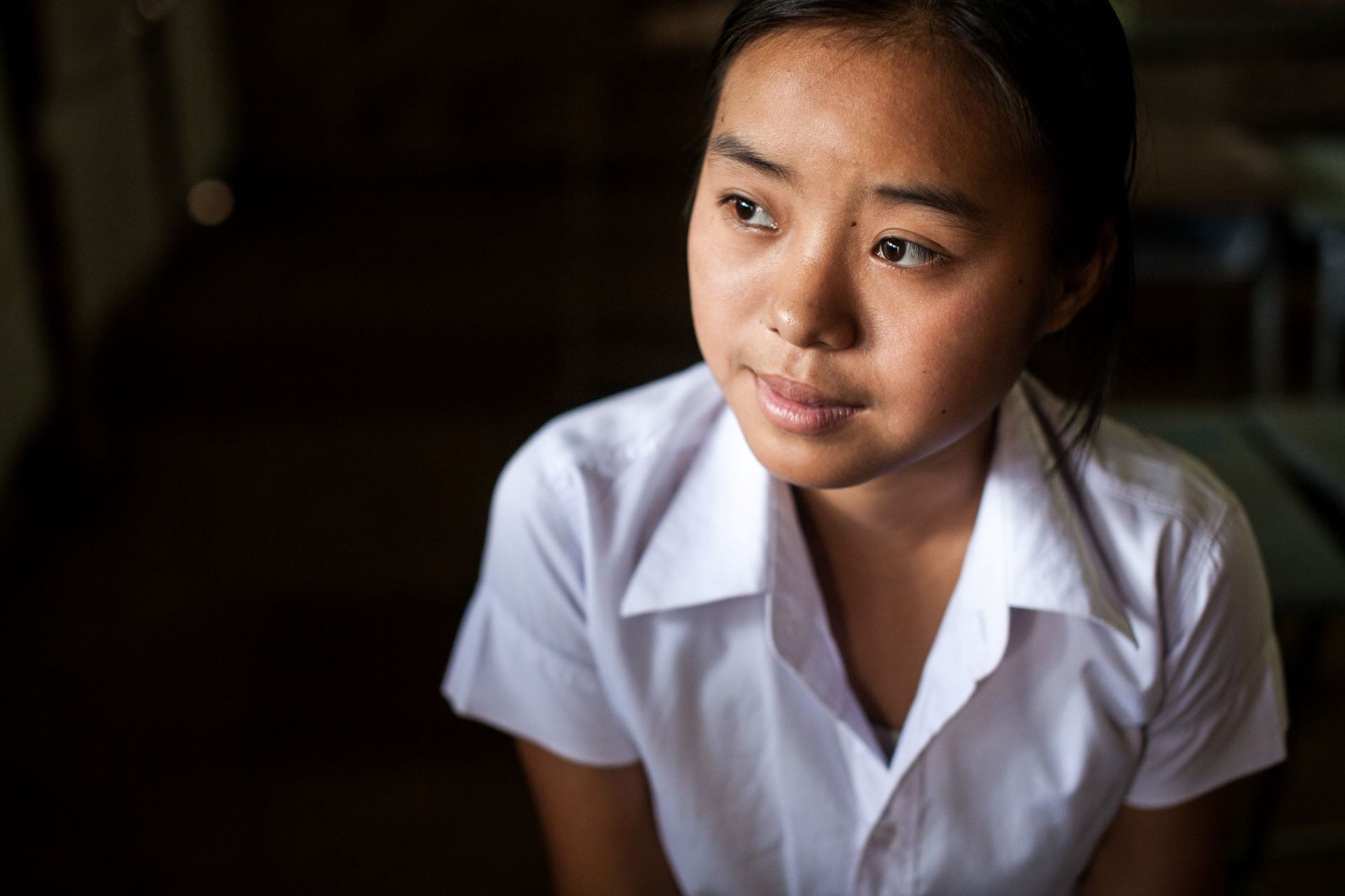 Lähikuva valkoiseen kauluspaitaan pukeutuneesta nuoresta myanmarilaisnaisesta.