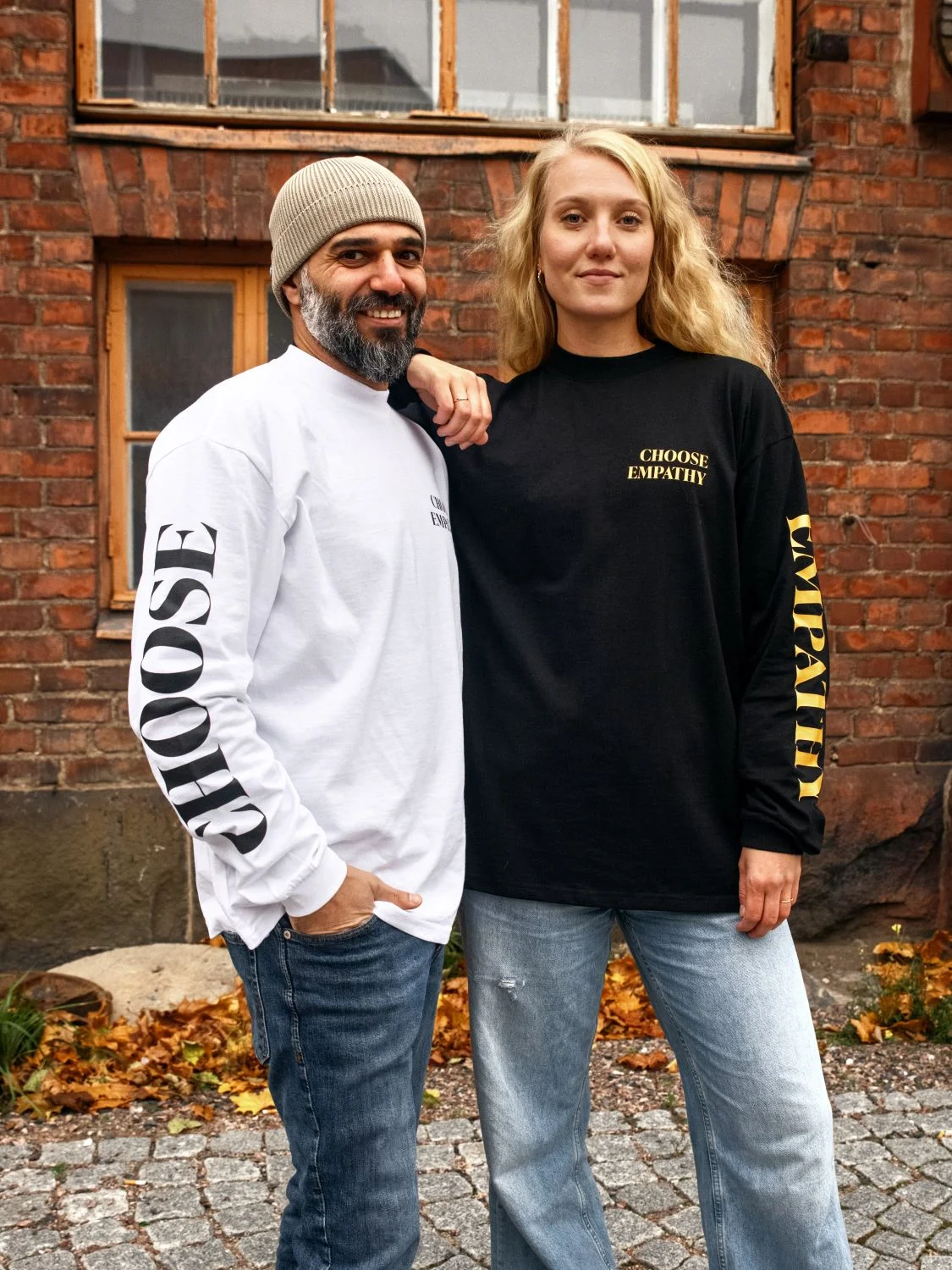 Kuvassa on mies ja nainen, joka nojaa mieheen pitäen kyynärvarttaan miehen hartialla. Miehellä on päällään valkoinen pitkähihainen, ohuesta materiaalista valmistettu collegepaita, jonka oikeanpuoleiseen hihaan on kirjoitettu isolla, mustalla tekstillä sana "choose". Paidan etumuksessa vasemmalla puolella lukee pienemmällä mustalla tekstillä "choose empathy" siten, että sanat ovat allekkain. Naisella on päällään musta paita, jonka vasemmanpuoleisessa hihassa lukee isolla, lämpimän keltaisella tekstillä "empathy". Paidan etumuksessa vasemmalla lukee pienemmällä, lämpimänkeltaisella tekstillä "choose empathy". Molemmissa paidoissa on solisluun yläpuolelle tuleva kaulus.